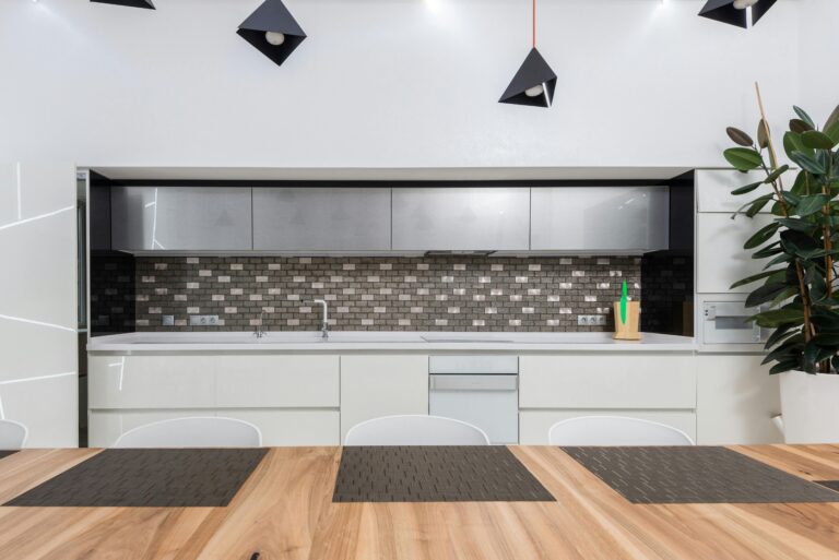 Modern minimalist kitchen featuring a grey textured peel and stick backsplash, white cabinetry, and warm wood dining table, illustrating renter-friendly quiet luxury decor.