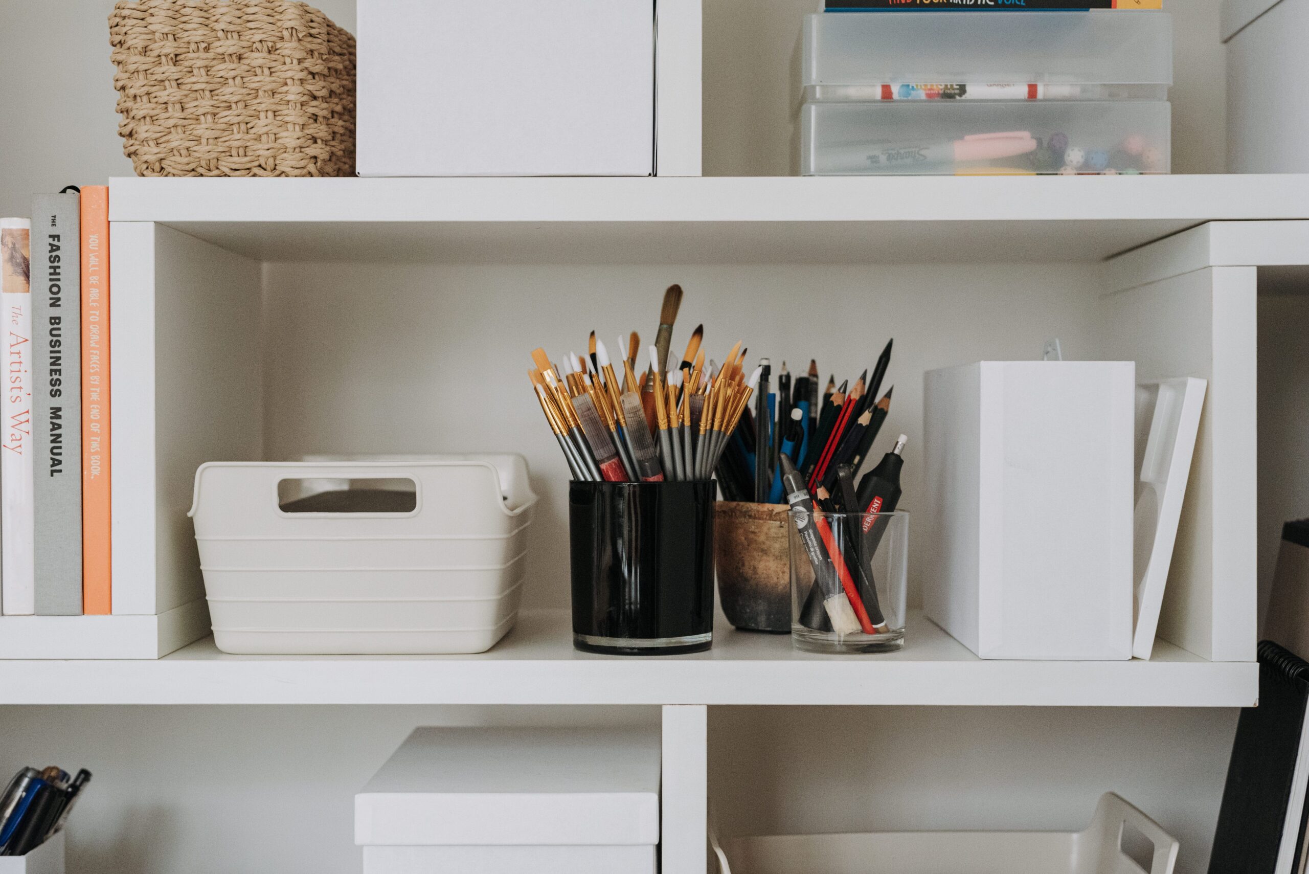 Minimalist white shelving unit with organized storage boxes and baskets, illustrating CubeSmart self storage ideas for small spaces.