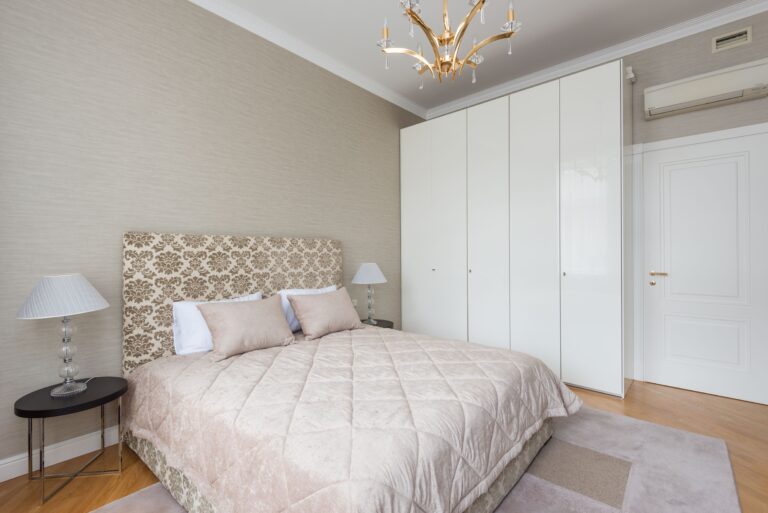 Feng shui bed placement in a calm rental bedroom with the headboard against a solid wall and the door in view