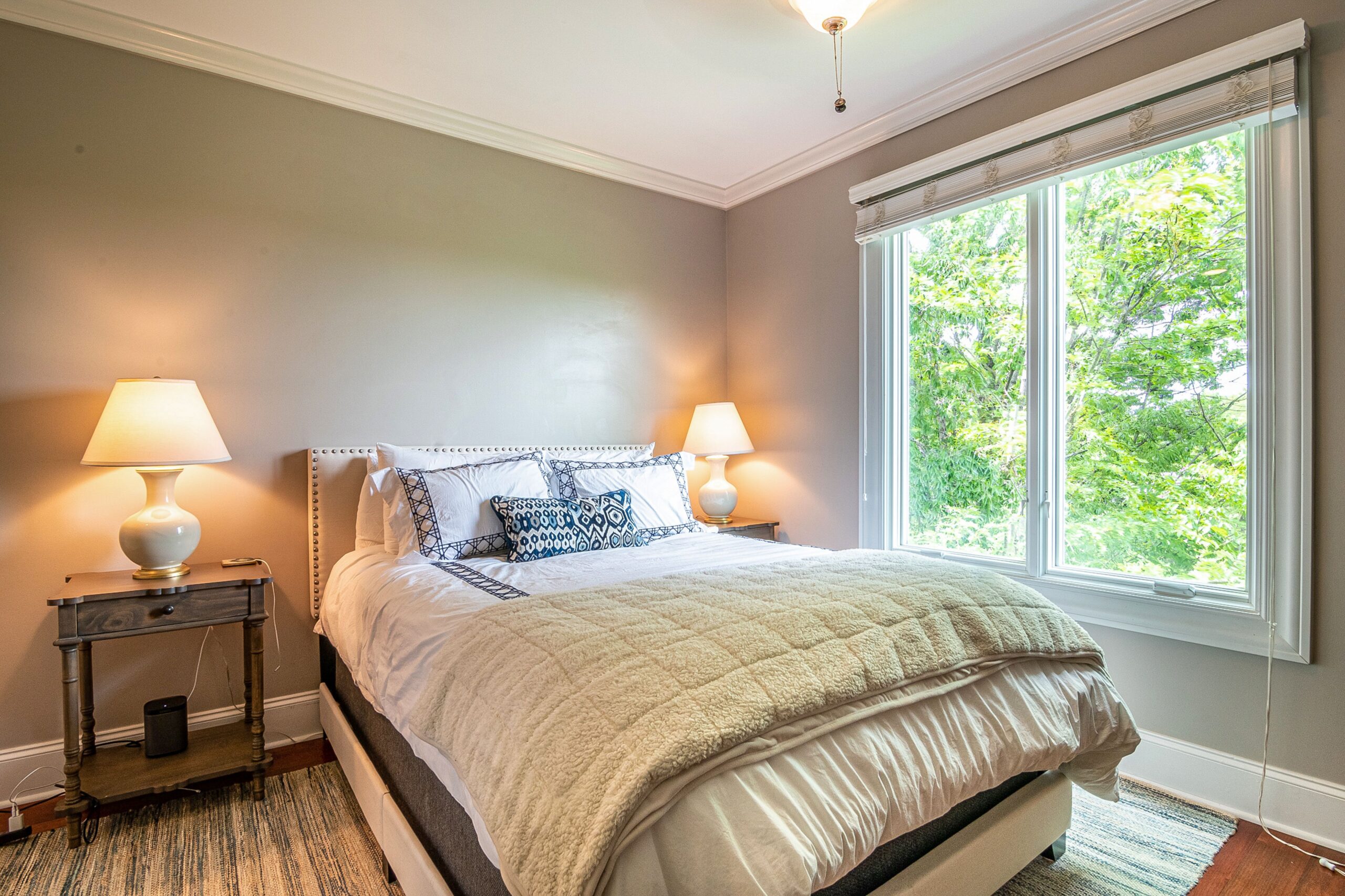 Renter-friendly feng shui bed placement with a freestanding headboard, plug-in wall sconce, and area rug